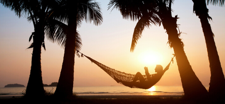 woman lying in hammock on beach at sunset
