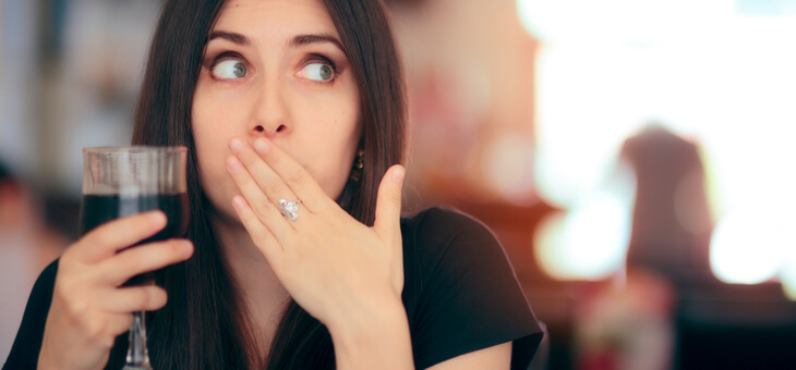 woman covering mouth looking embarrassed
