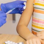 small child receiving vaccine injection from nurse