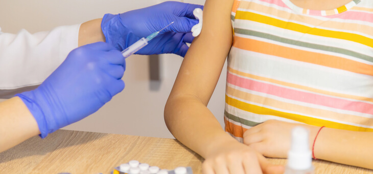 small child receiving vaccine injection from nurse