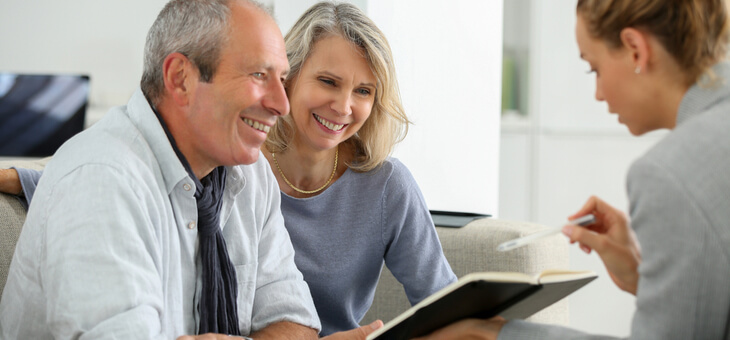 smiling older couple speaking with financial planner