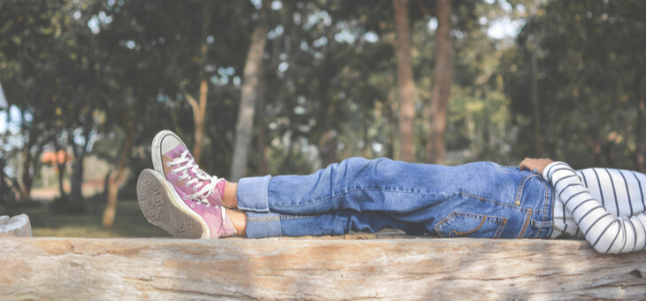 legs of young girl lying on top of wooden fence