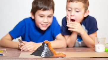 two boys watching a baking soda volcano science experiment