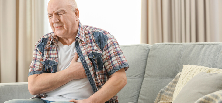 man on couch with hand on chest
