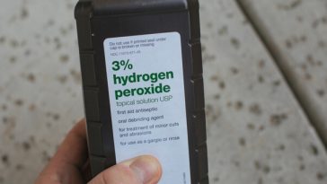 hand holding bottle labelled hydrogen peroxide