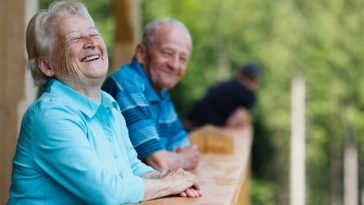 older couple standing on deck laughing
