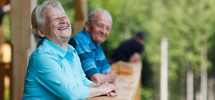 older couple standing on deck laughing