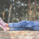 legs of young girl lying on top of wooden fence