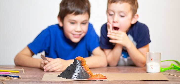 two boys watching a baking soda volcano science experiment