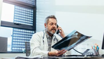 doctor in office on phone holding xrays