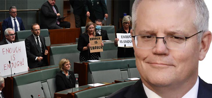 scott morrison with a smarmy look on his face while politicians in the background hold up enough is enough signs in parliament