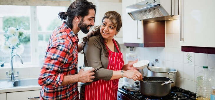 woman stirring pot on stove while adult son looks over shoulder
