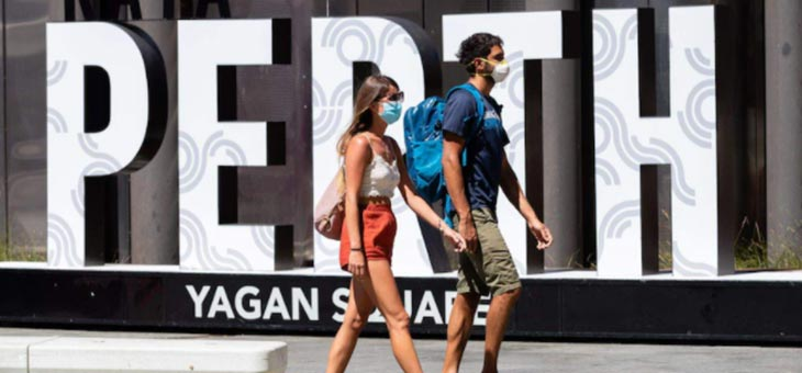 couple walking in front of a perth sign