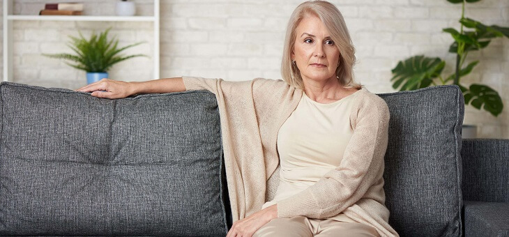 woman sitting on couch looking uncomfortable
