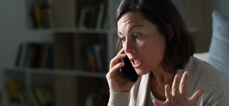 woman looking frustrated while speaking on phone