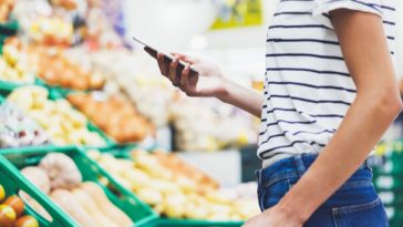 woman looking at phone in supermarket