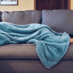 woman lying on couch under blanket