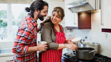 woman stirring pot on stove while adult son looks over shoulder
