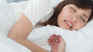 woman lying in bed clenching her teeth
