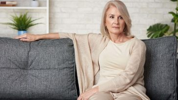 woman sitting on couch looking uncomfortable