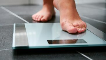feet of woman stepping on bathroom scales