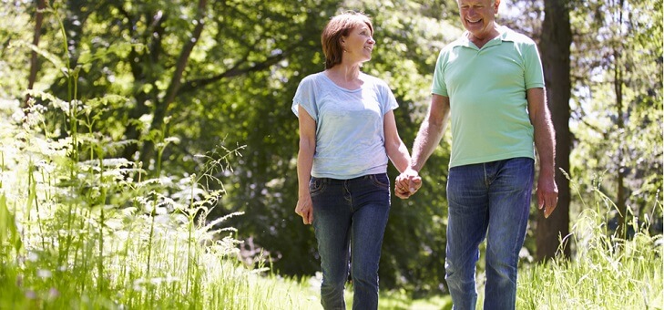 happy older couple walking hand in hand in park