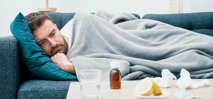 man lying on his couch sick with covid