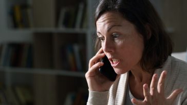 woman looking frustrated while speaking on phone