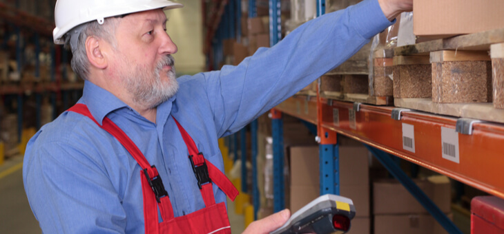 older man in hard hat and overalls working in warehouse