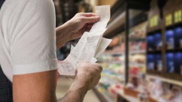 man looking at receipt in supermarket
