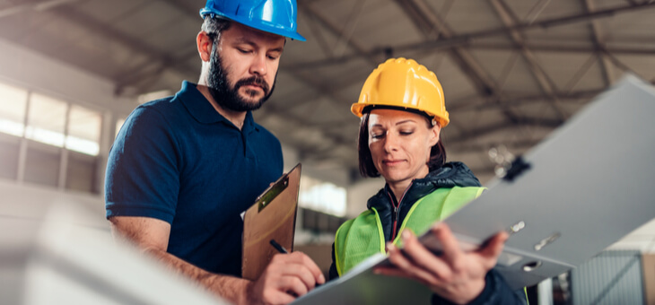 man and woman in hard hats discussing plans on job site