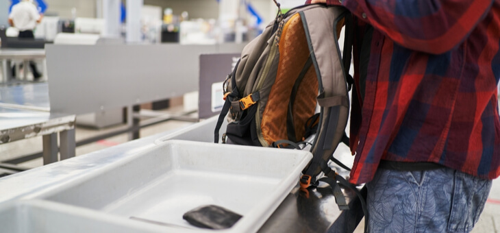 man emptying backpack at airport security