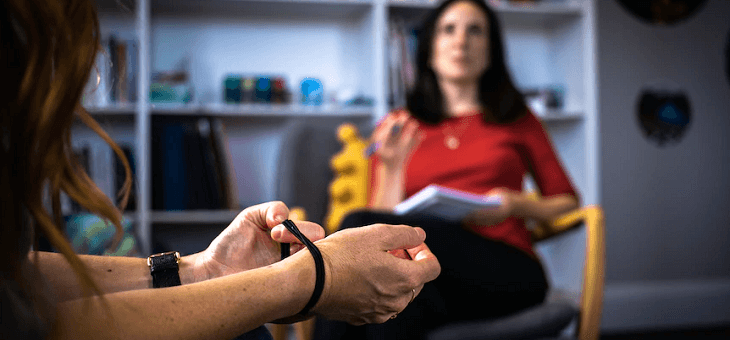 woman pulling rubber band on wrist while speaking to therapist