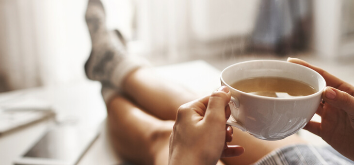 person relaxing on couch with cup of tea