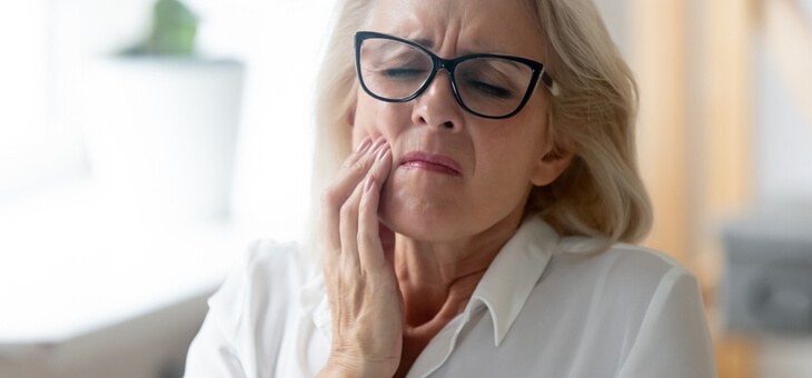 mature woman holding jaw in pain