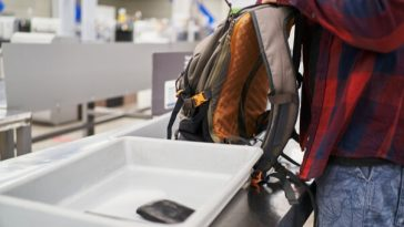 man emptying backpack at airport security