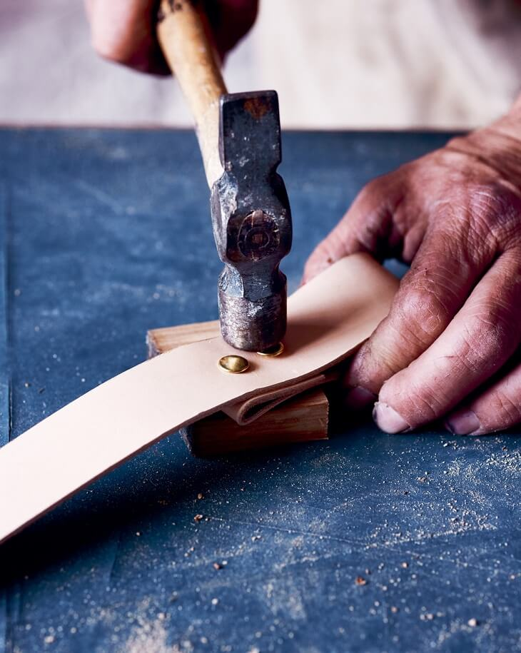 man hammering nail into piece of wood
