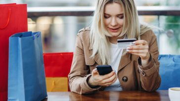woman holding credit card in one hand and smartphone in the other