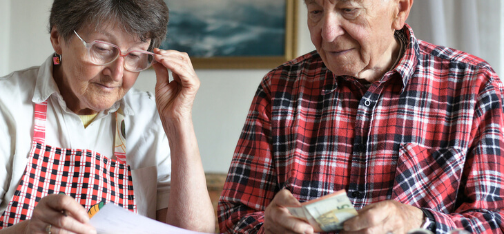 elderly couple going over bills at kitchen table