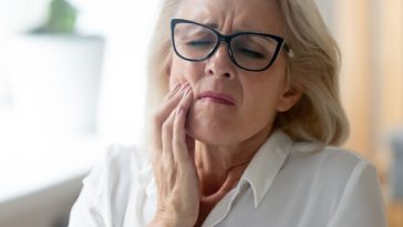 mature woman holding jaw in pain