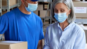 mature woman wearing mask at work receiving delivery