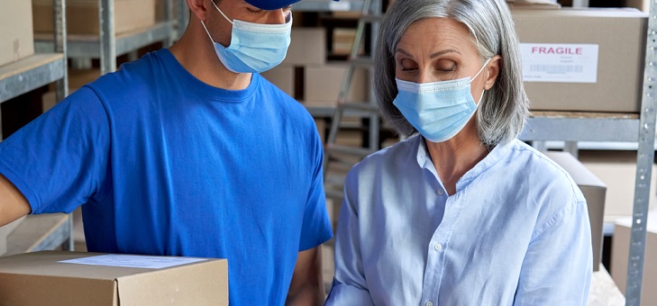 mature woman wearing mask at work receiving delivery
