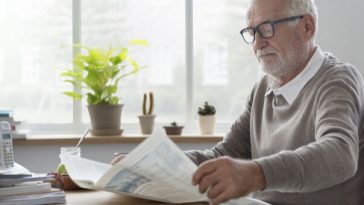 older man reading newspaper at kitchen table