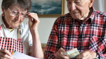 elderly couple going over bills at kitchen table