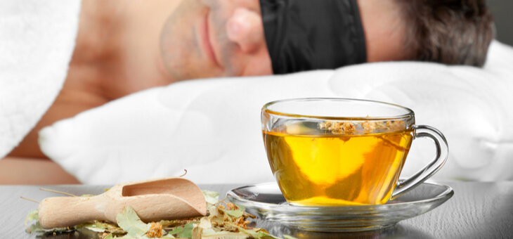 cup of herbal tea on bedside table next to sleeping man