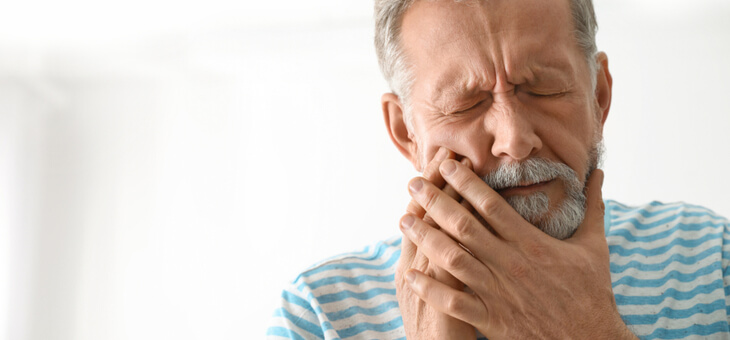 man wincing in pain holding mouth