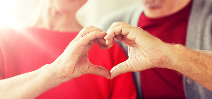 older couple making heart shape by joining hands
