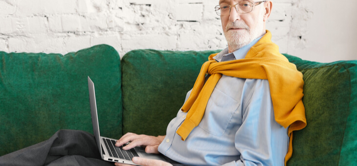 older man using laptop on couch
