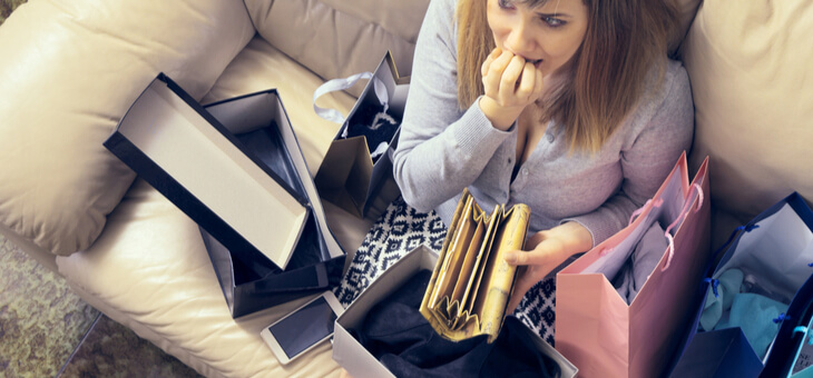 woman looking in empty wallet while surrounded by purchases