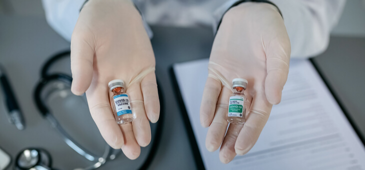 gloved hands holding two different covid vaccines